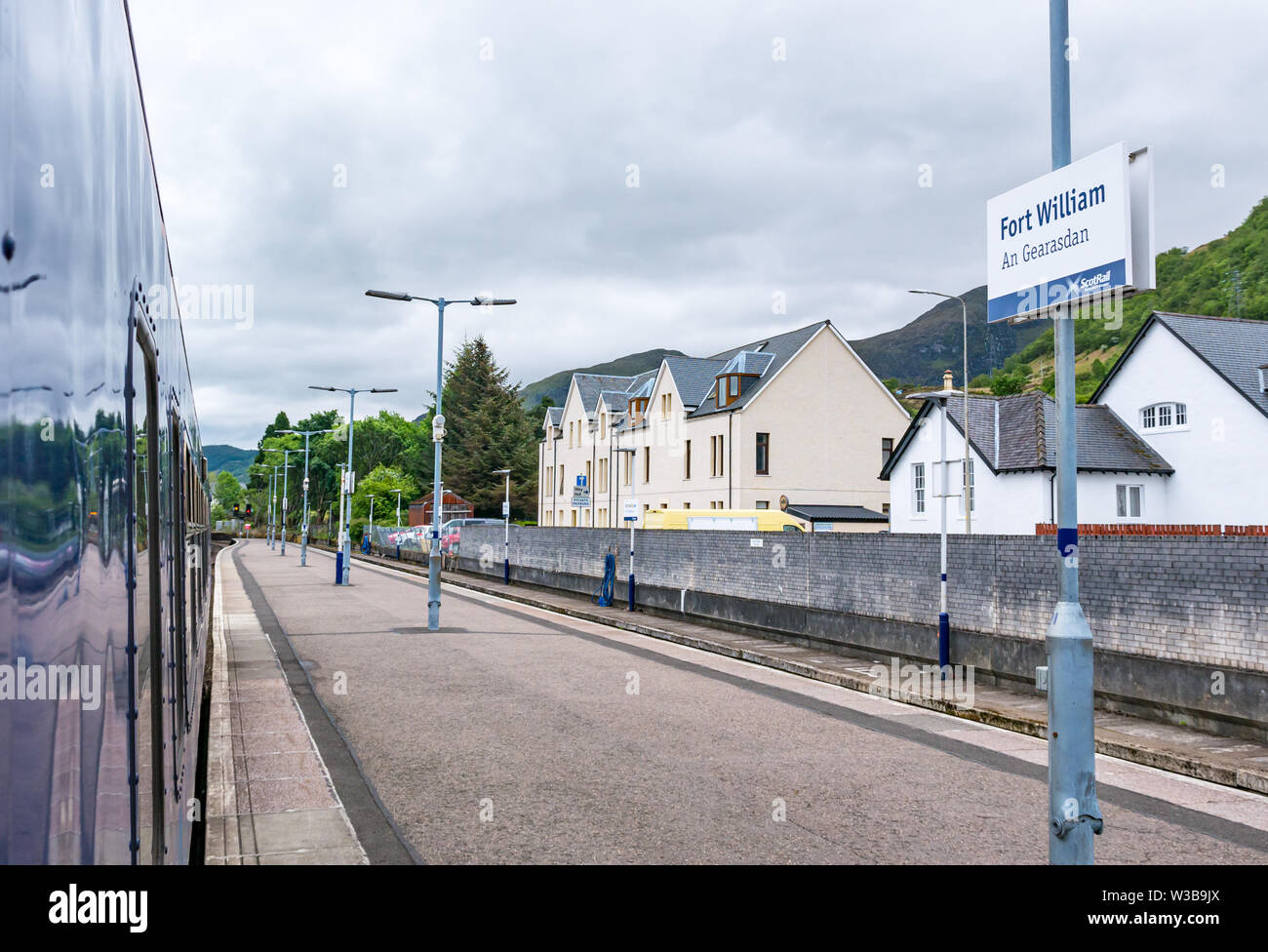 Fort William stazione ferroviaria piattaforma e nome sign con treno ScotRail su West Highland linea ferroviaria, Highlands scozzesi, Scotland, Regno Unito Foto Stock