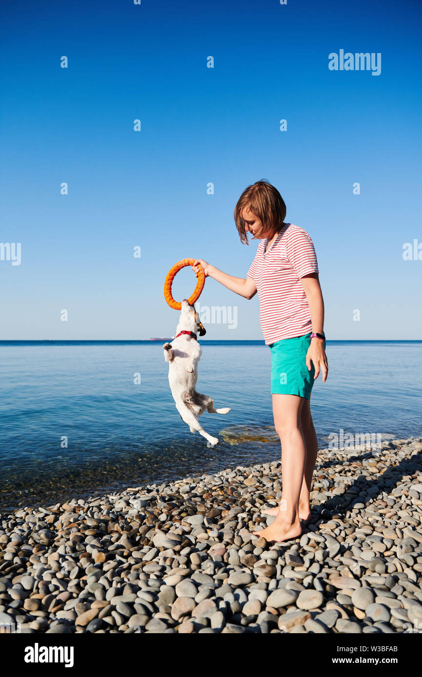 La donna gioca con il suo cane sulla costa del mare Foto Stock