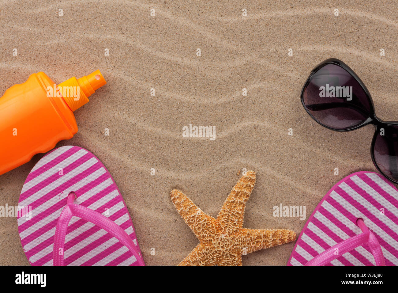 Accessori da spiaggia in sabbia. Le infradito e occhiali da sole. Vista dall'alto. Foto Stock