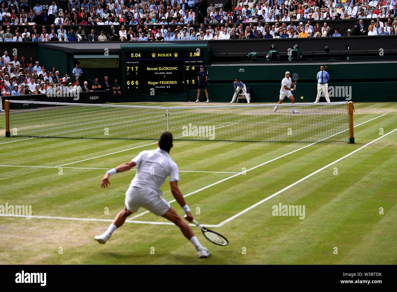 Roger Federer e Novak Djokovic (fondo) in azione nella mens singles finale del giorno tredici dei campionati di Wimbledon al All England Lawn Tennis e Croquet Club, Wimbledon. Foto Stock