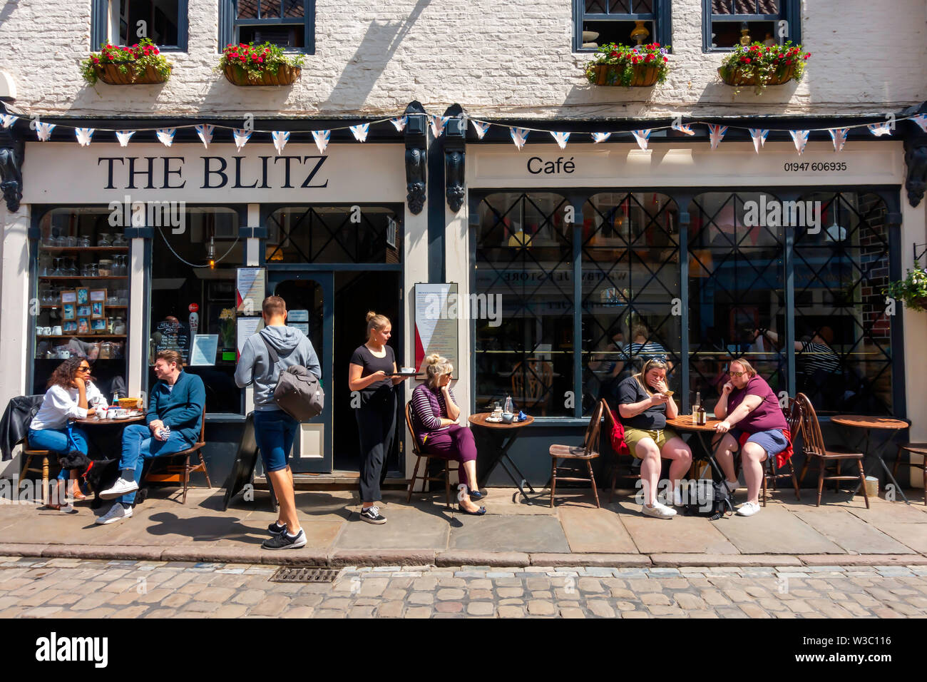 Ai clienti di godere di un sole estivo alfresco al di fuori del blitz caffetteria in Church street a Whitby North Yorkshire England Regno Unito Foto Stock