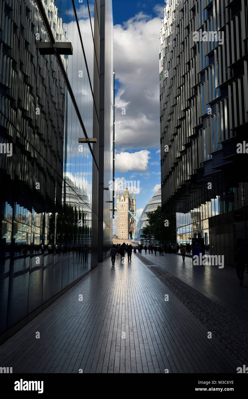 In granito lucido lastricatori su più Londra Riverside passaggio pedonale con riflessioni in edifici in vetro del Tower Bridge e City Hall London Inghilterra England Foto Stock