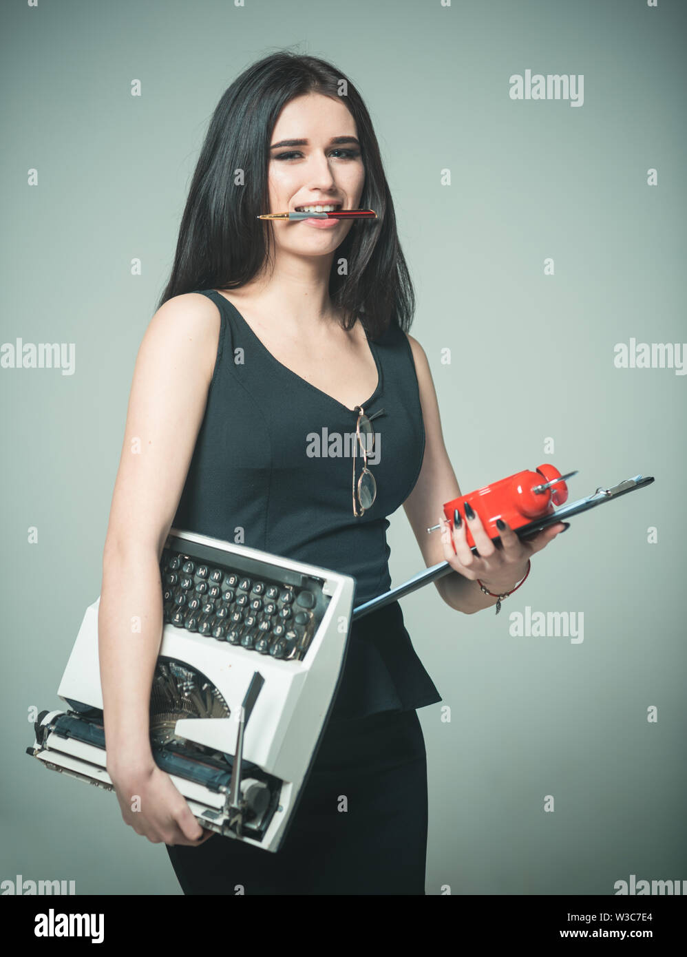 Signora maestra porta i nastri inchiostratori per macchine da scrivere sveglia e pianificazione. Concetto di multitasking. Signora un multitasking positivo. Ragazza detiene penna in denti. Appena in tempo Foto Stock