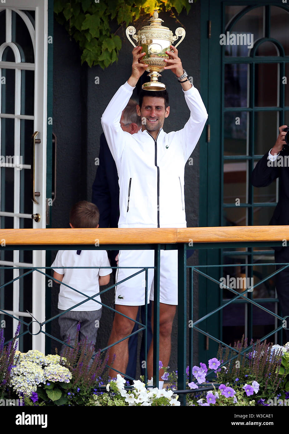 Novak Djokovic mostra il trofeo agli appassionati da una corte centrale balcone dopo aver battuto Roger Federer nella mens singles finale del giorno tredici dei campionati di Wimbledon al All England Lawn Tennis e Croquet Club, Wimbledon. Foto Stock