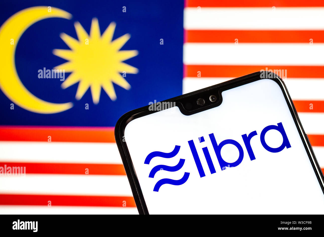 Facebook Libra crypto logo valuta sullo smartphone e sfocata bandiera della Malaysia a uno schermo portatile sullo sfondo. Foto concettuale. Foto Stock