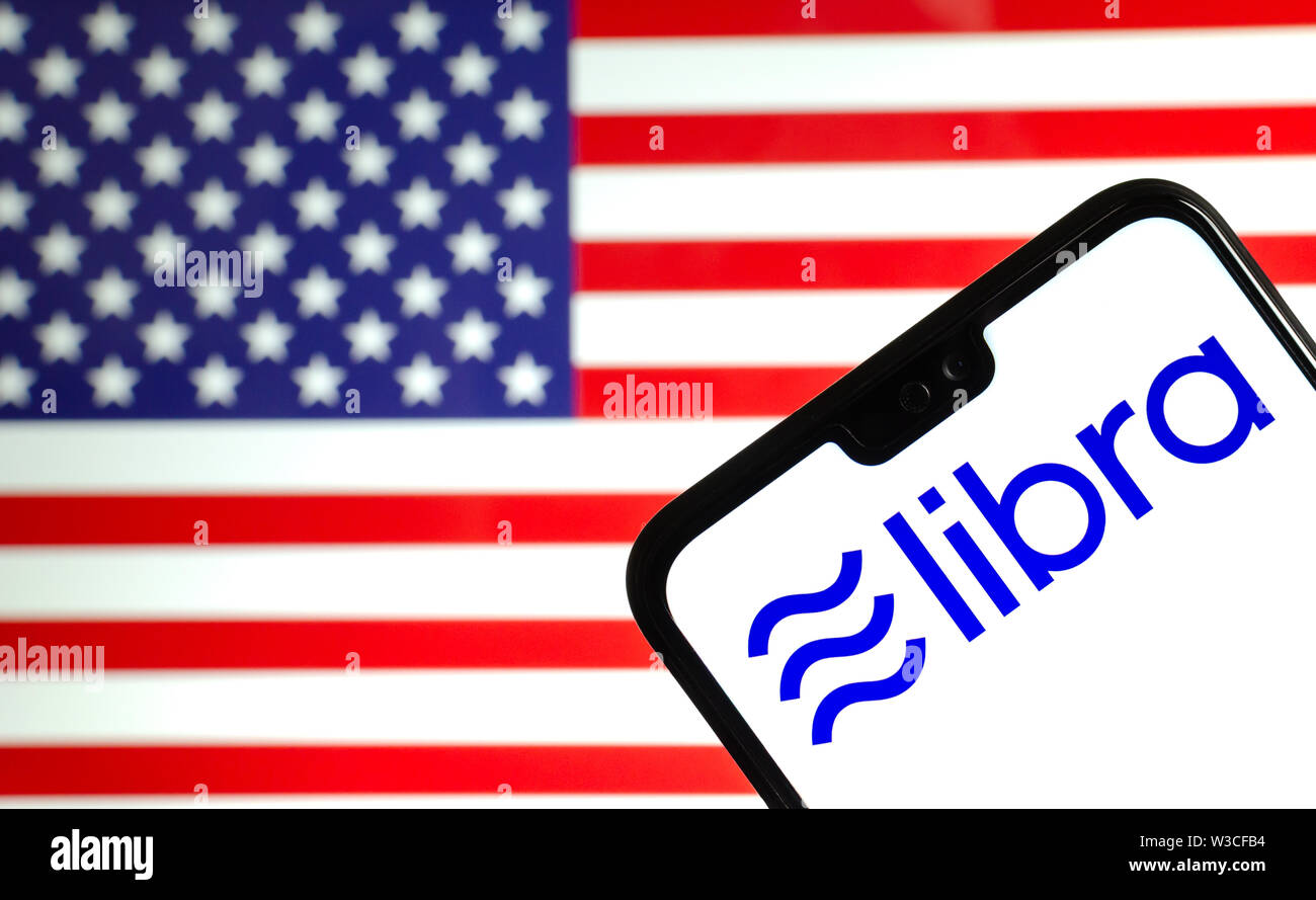 Facebook Libra crypto logo valuta sullo smartphone e sfocata bandiera degli stati uniti in corrispondenza di uno schermo portatile sullo sfondo. Foto concettuale. Foto Stock