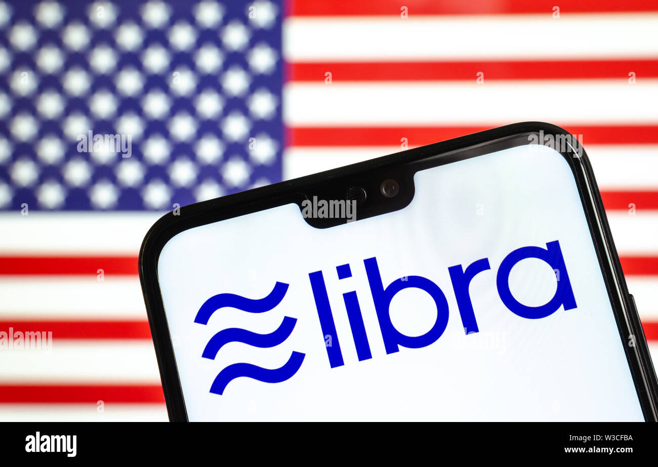 Facebook Libra crypto logo valuta sullo smartphone e sfocata bandiera degli stati uniti in corrispondenza di uno schermo portatile sullo sfondo. Foto concettuale. Foto Stock