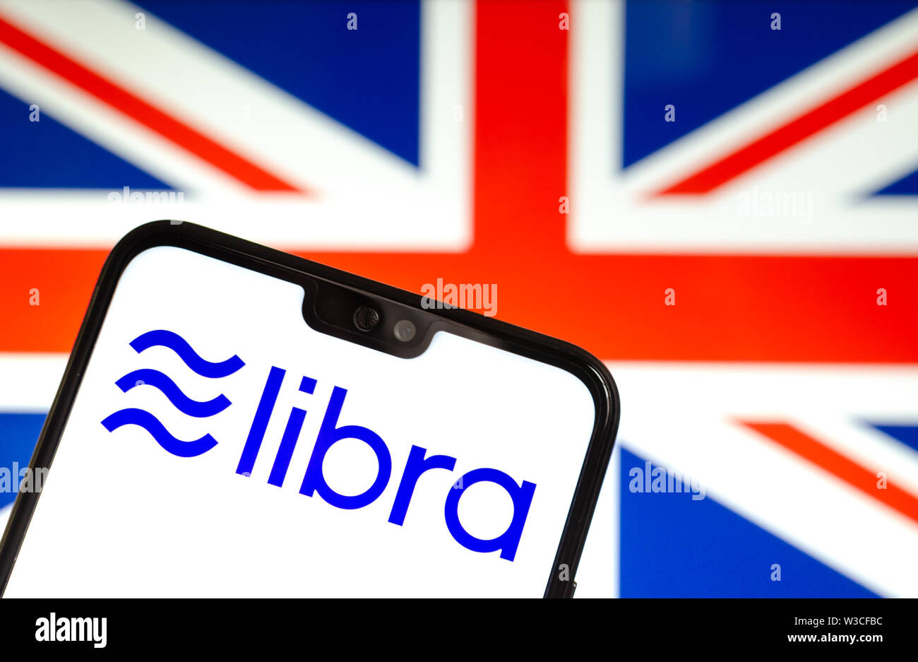 Facebook Libra crypto logo valuta sullo smartphone e sfocata bandiera del Regno Unito a uno schermo portatile sullo sfondo. Foto concettuale. Foto Stock