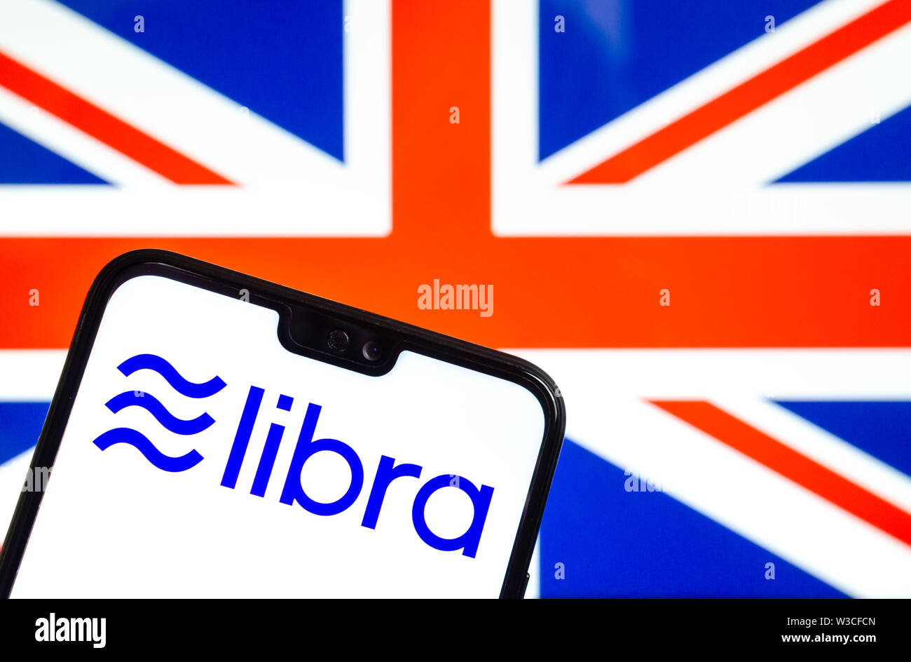 Facebook Libra crypto logo valuta sullo smartphone e sfocata bandiera del Regno Unito a uno schermo portatile sullo sfondo. Foto concettuale. Foto Stock