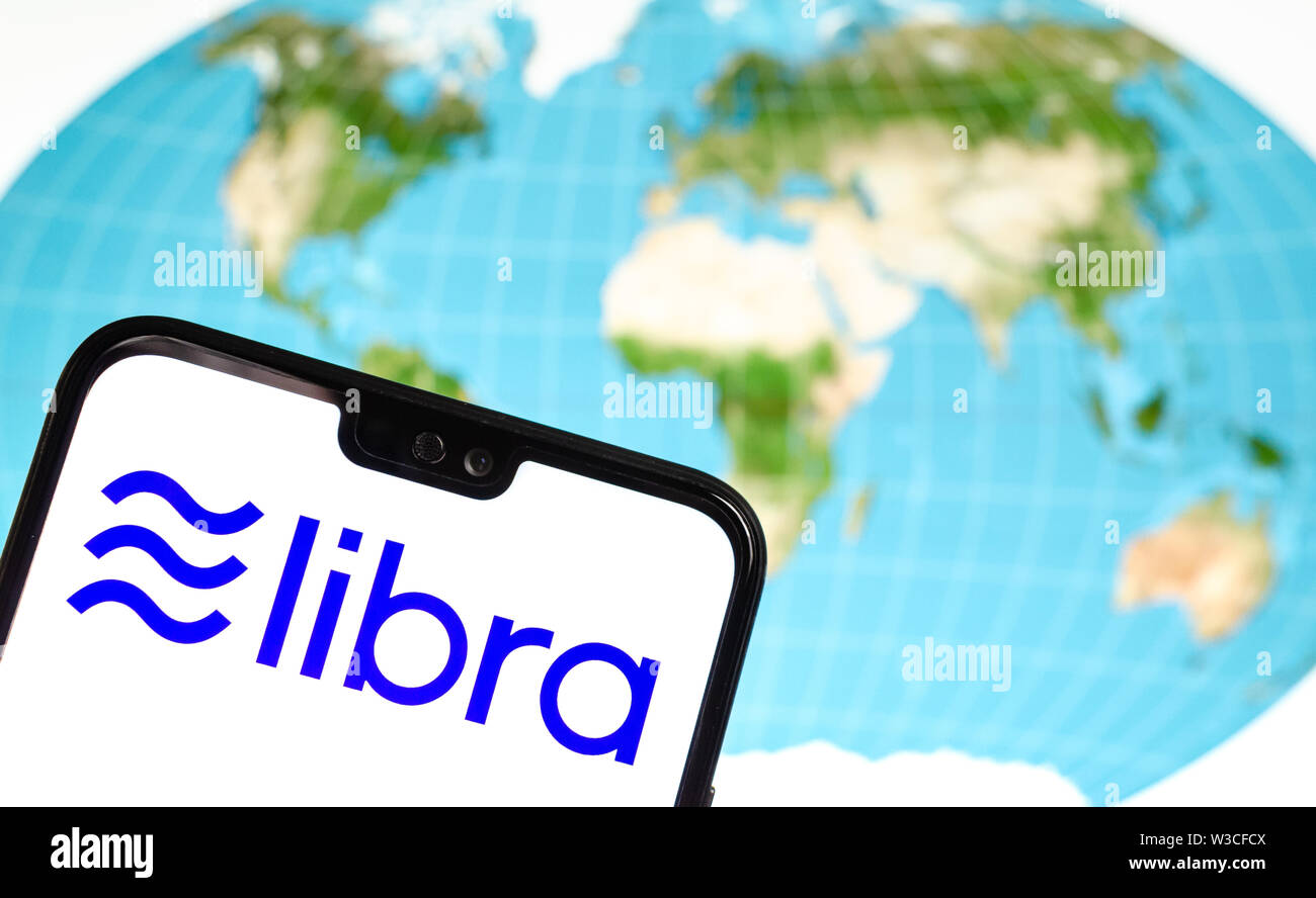 Facebook Libra crypto cambio logo sullo smartphone e la mappa del mondo in una schermata di un laptop sullo sfondo. Foto concettuale. Foto Stock