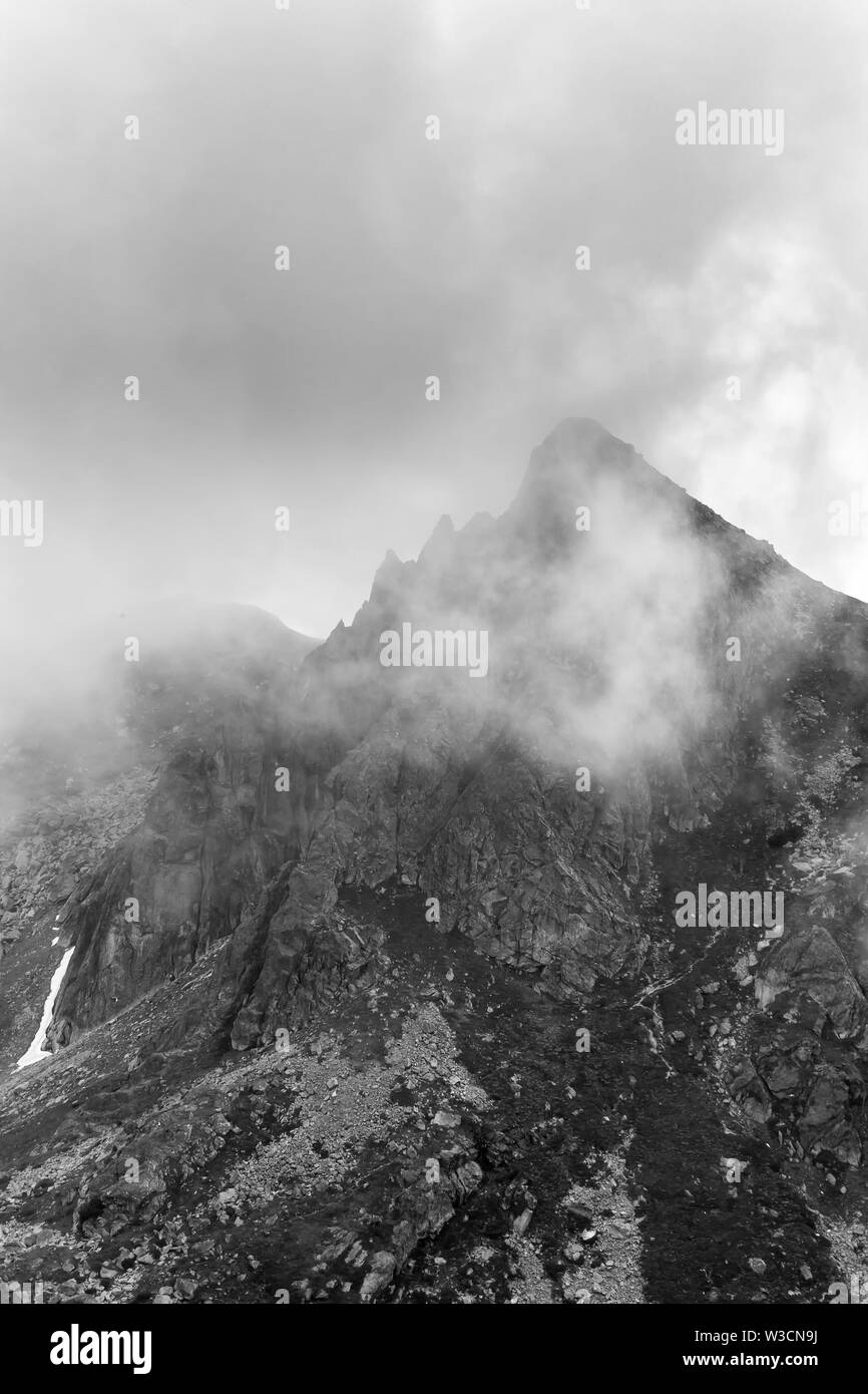Visualizzazione bianco e nero del vertice appuntito sulla montagna Rila in Bulgaria coperti dalla nebbia drammatico visto dal lago di picco Foto Stock