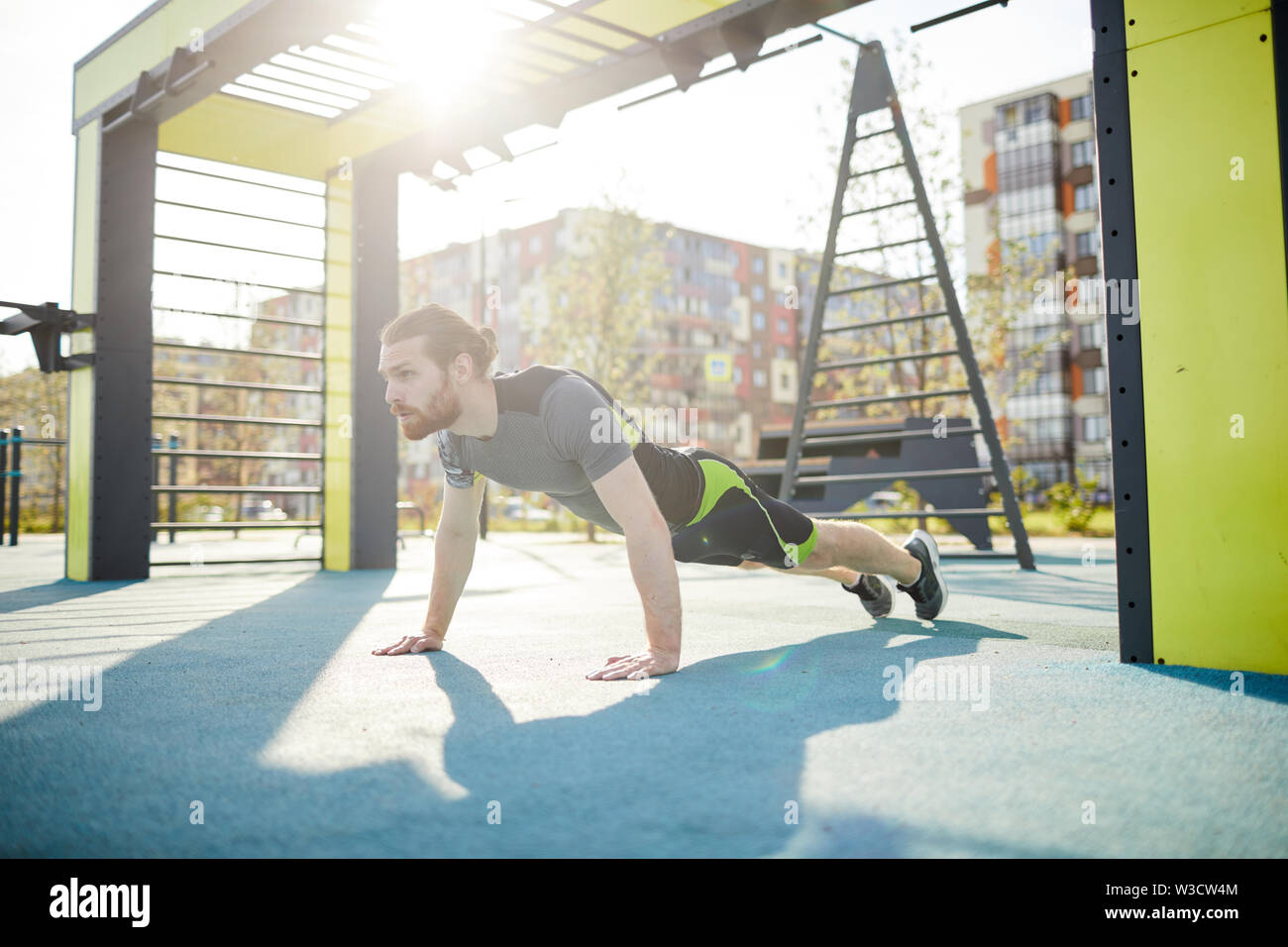 Potente concentrato giovane atleta in sportswear spingere voi lontano dal suolo mentre il training da soli Foto Stock