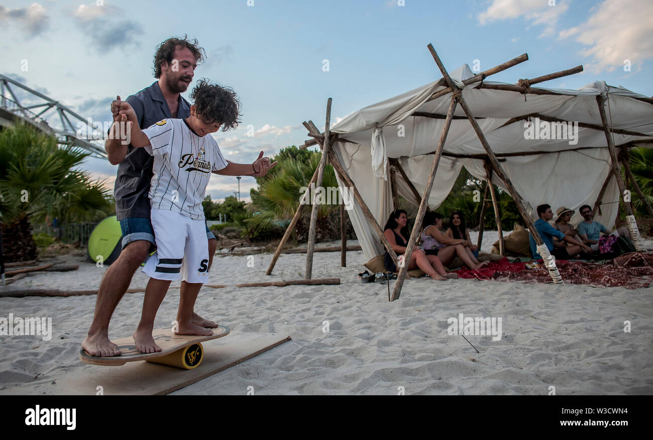 Atene, Grecia. 14 Luglio, 2019. Un bambino cerca di acrobazie con la guida di un istruttore durante il Surf Art Festival di Atene, Grecia, il 14 luglio 2019. Il Surf Art Festival è una tre giorni di festival dedicato all'arte del vivere e del surf. Credito: Panagiotis Moschandreou/Xinhua/Alamy Live News Foto Stock