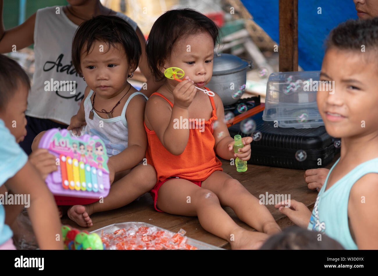 Una giovane ragazza filippina con altri bambini in una comunità povera soffiare bolle,Cebu City, Filippine Foto Stock