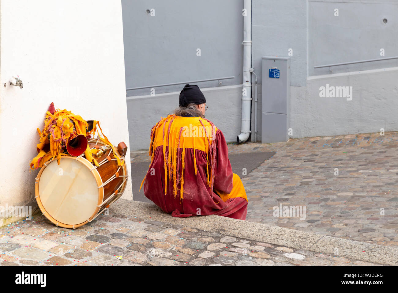 Martinskirchplatz, Basilea, Svizzera - Marzo 12th, 2019. Il carnevale unico partecipante con costume arancione e un tamburo rullante Foto Stock