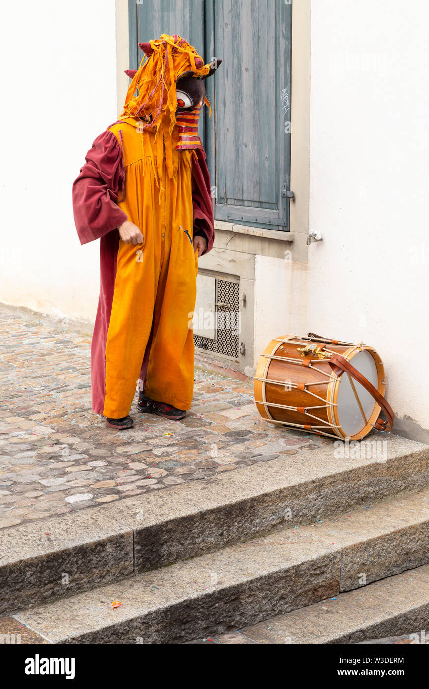 Martinskirchplatz, Basilea, Svizzera - Marzo 12th, 2019. Il carnevale unico partecipante con costume arancione e un tamburo rullante Foto Stock