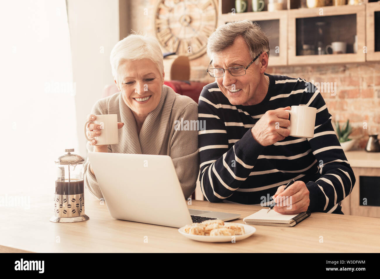 Allegro coppia senior guardando il laptop in cucina Foto Stock