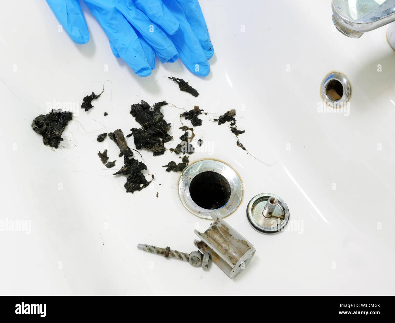 Lavandino intasato con massa di capelli e sporcizia in bagno. Foto Stock