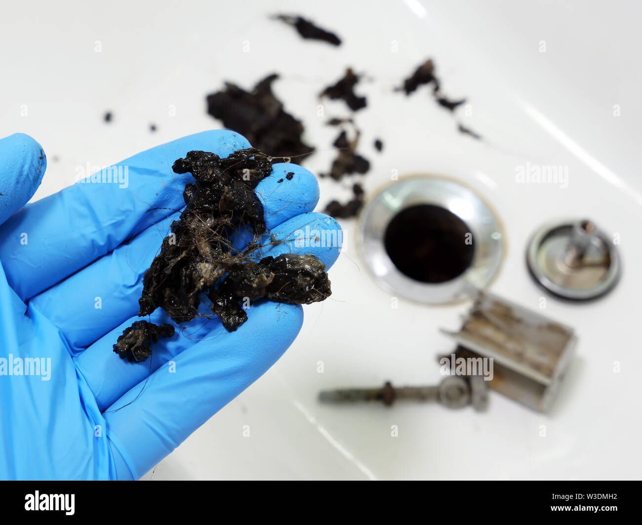 Plumber tenendo la massa di capelli e sporcizia dalla intasato lavandino. Foto Stock