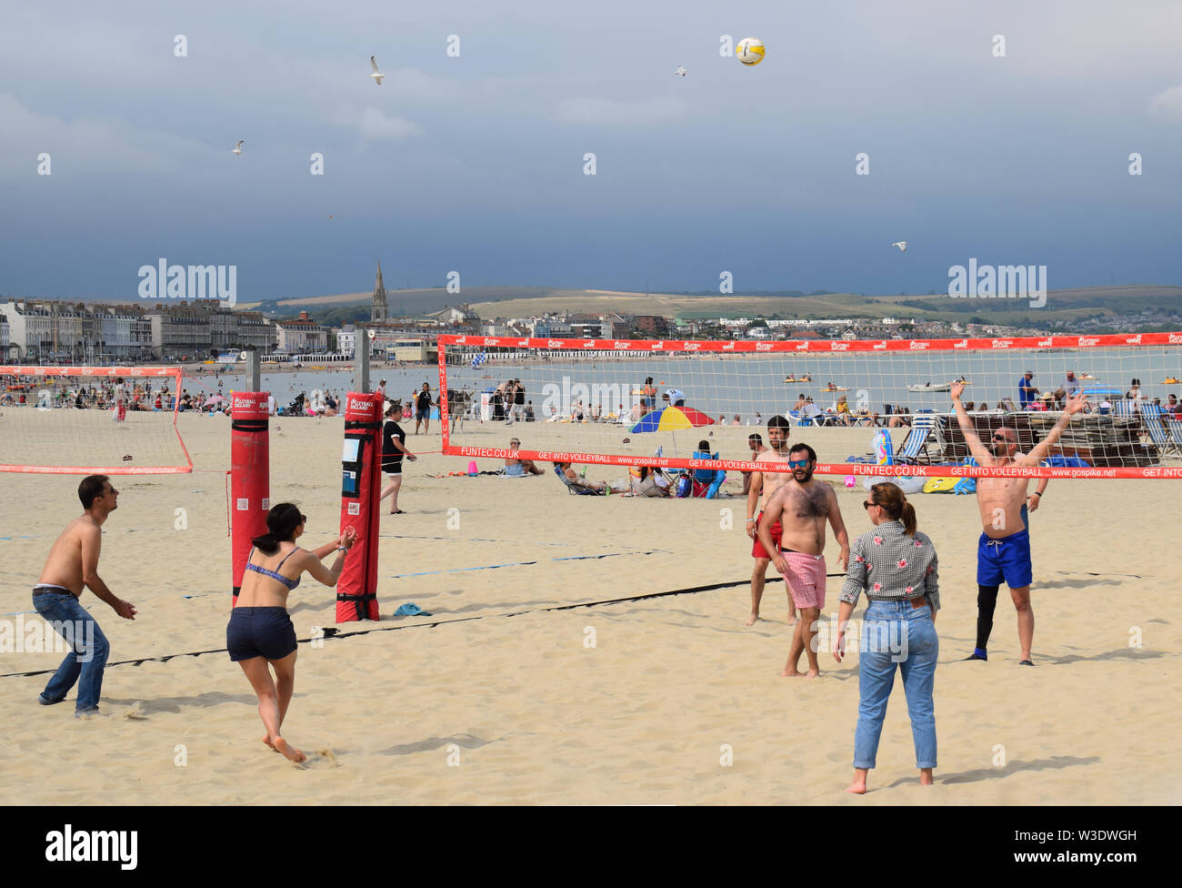 Persone a giocare a beach volley in estate sulla spiaggia di Weymouth nel Regno Unito Foto Stock