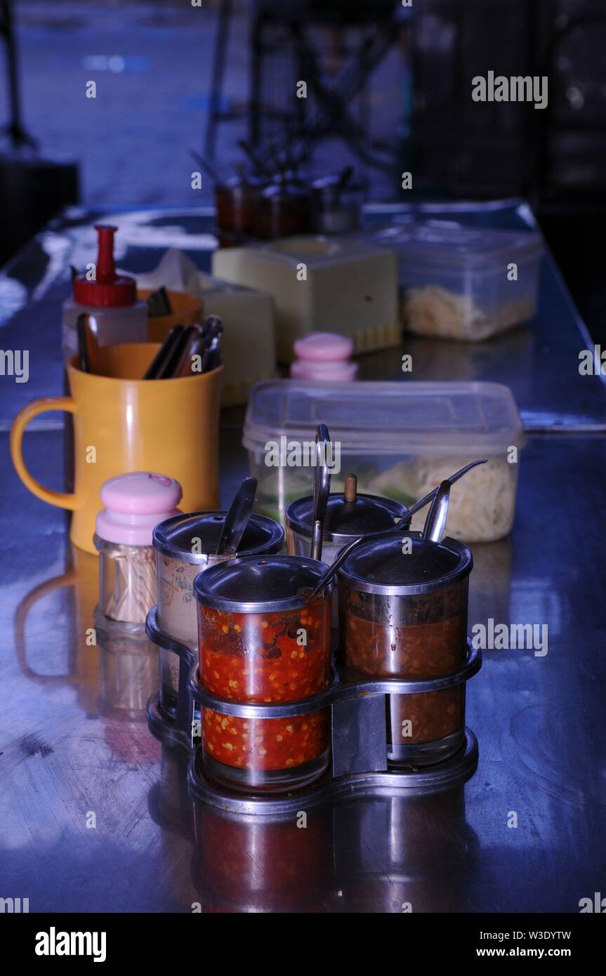 Condimenti su un ristorante a cielo aperto tavolo, tra cui salsa chili, al mercato russo, Phnom Penh Cambogia. Credito: Kraig Lieb Foto Stock