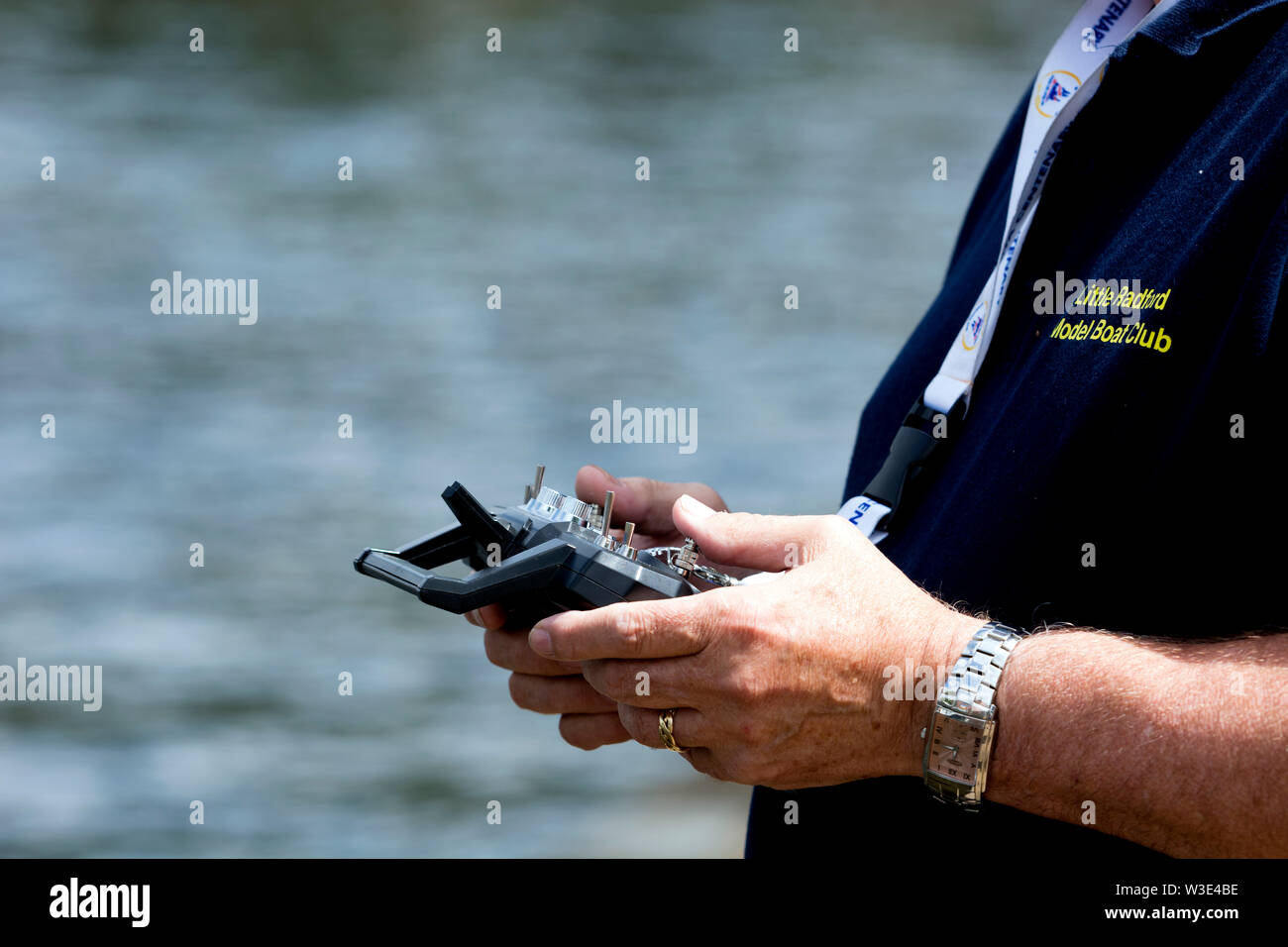 Un uomo che utilizza un dispositivo di controllo remoto per un modello di barca Foto Stock
