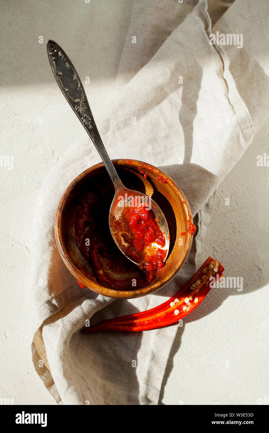 In casa tradizionale harissa-magrebino red hot chiles pasta con aglio e olio di oliva nel cucchiaio e ciotola vista dall'alto con copia spazio per il testo Foto Stock