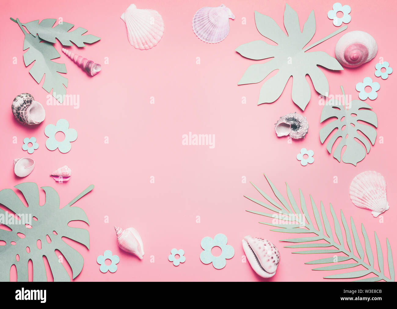Cornice di conchiglie di mare e foglie tropicali sul rosa pastello sfondo, vista dall'alto. Layout creativi. Lay piatto. Concetto di estate Foto Stock