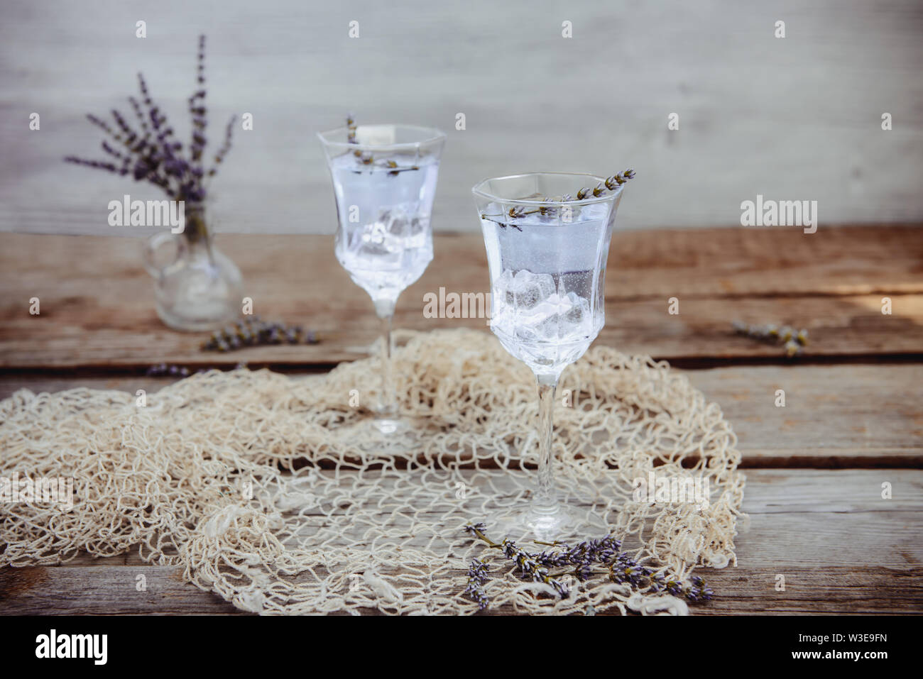 Fresca limonata di lavanda con i fiori e i cubetti di ghiaccio nella bellissima occhiali su tavola in legno rustico. Detox acqua. Bevanda estiva. La dieta cocktail. Selective fo Foto Stock