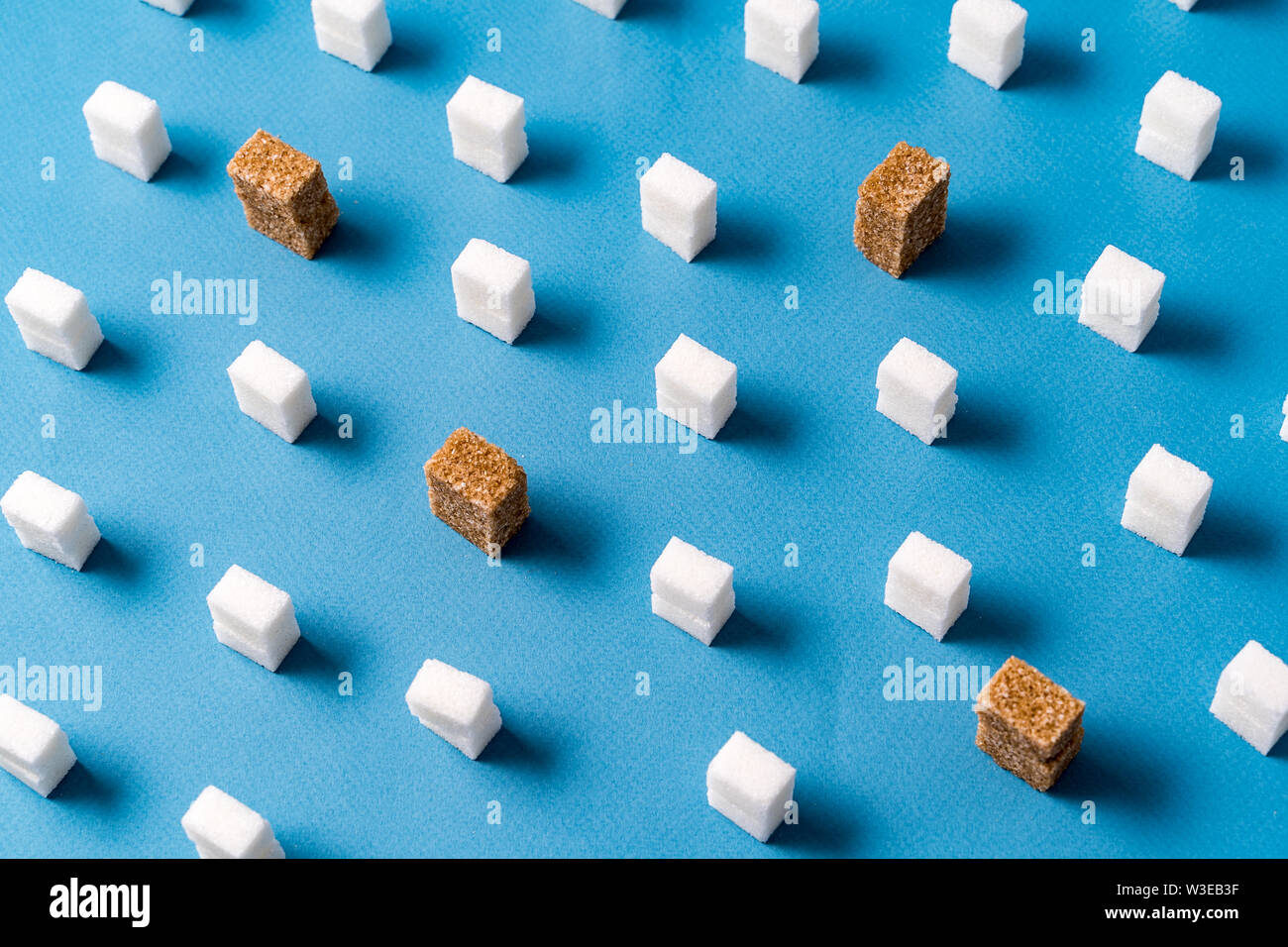 Vista superiore del bianco e del marrone cubetti di zucchero pattern su sfondo blu. Stile minimalista. Foto Stock