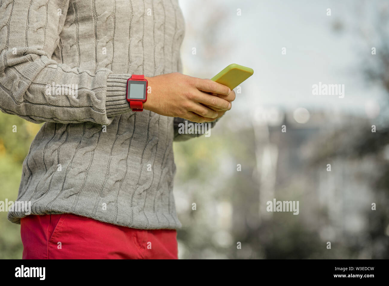 Uomo molto impegnato nel colore rosso brillante pantaloni e maglione grigio  avente orologio elettronico Foto stock - Alamy