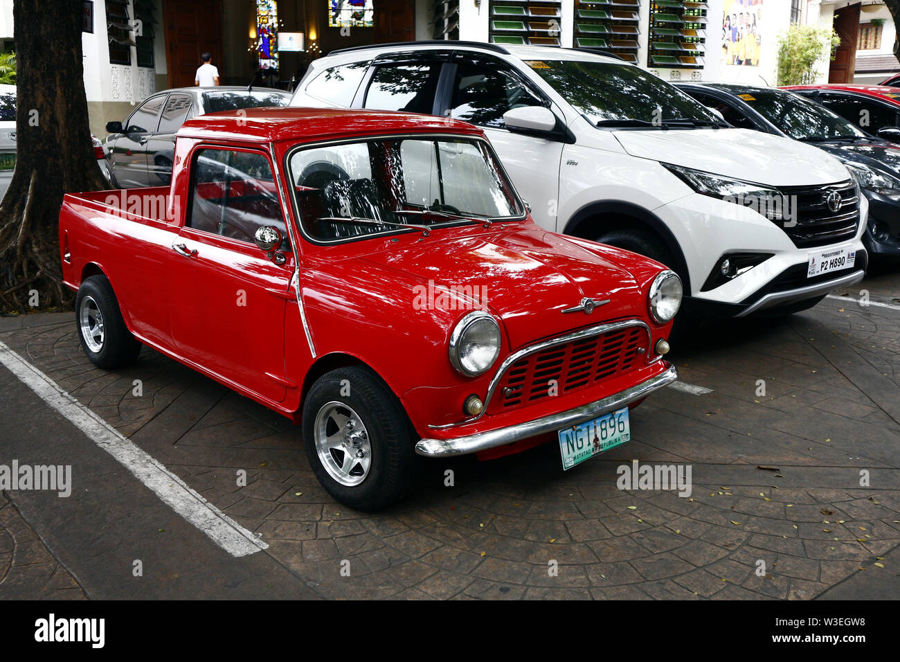 ANTIPOLO City, Filippine - 12 luglio 2019: un colore rosso classico e vintage mini auto parcheggiate accanto a un SUV moderno a un parcheggio pubblico. Foto Stock