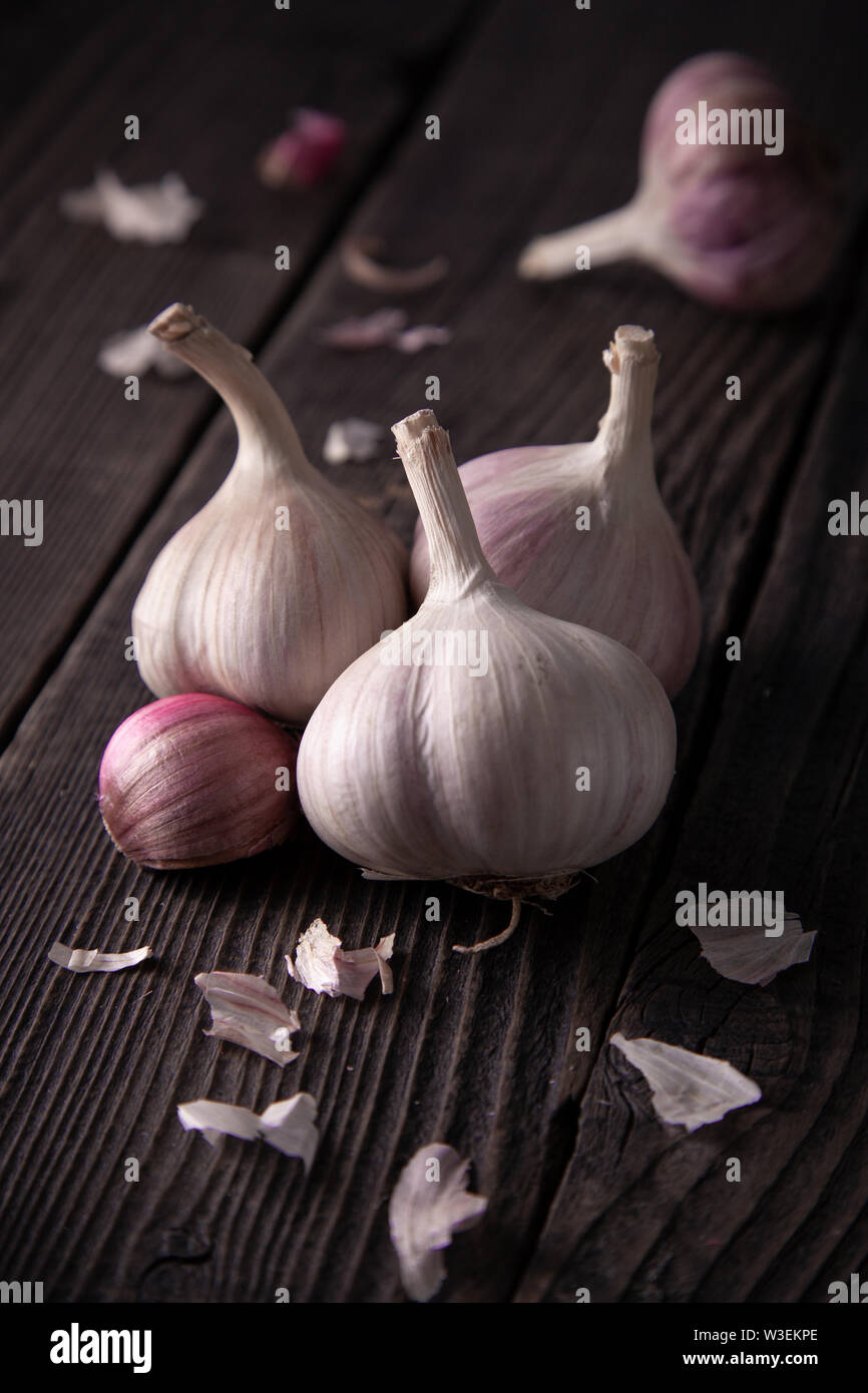 Teste d'aglio su una tavola di legno, naturali alimenti biologici. La cucina è una buona idea. Foto Stock