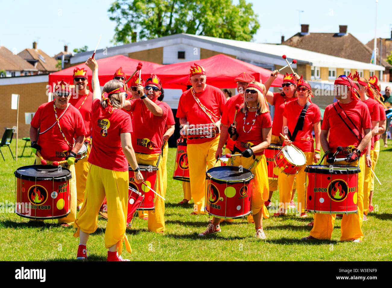 Mondo Tortino di crema campionato 2019. Bloco Fogo Samba Drumming Band. Banda in t-shirt rosse e pantaloni gialli, all'aperto, ronzio nel sole splendente. Foto Stock
