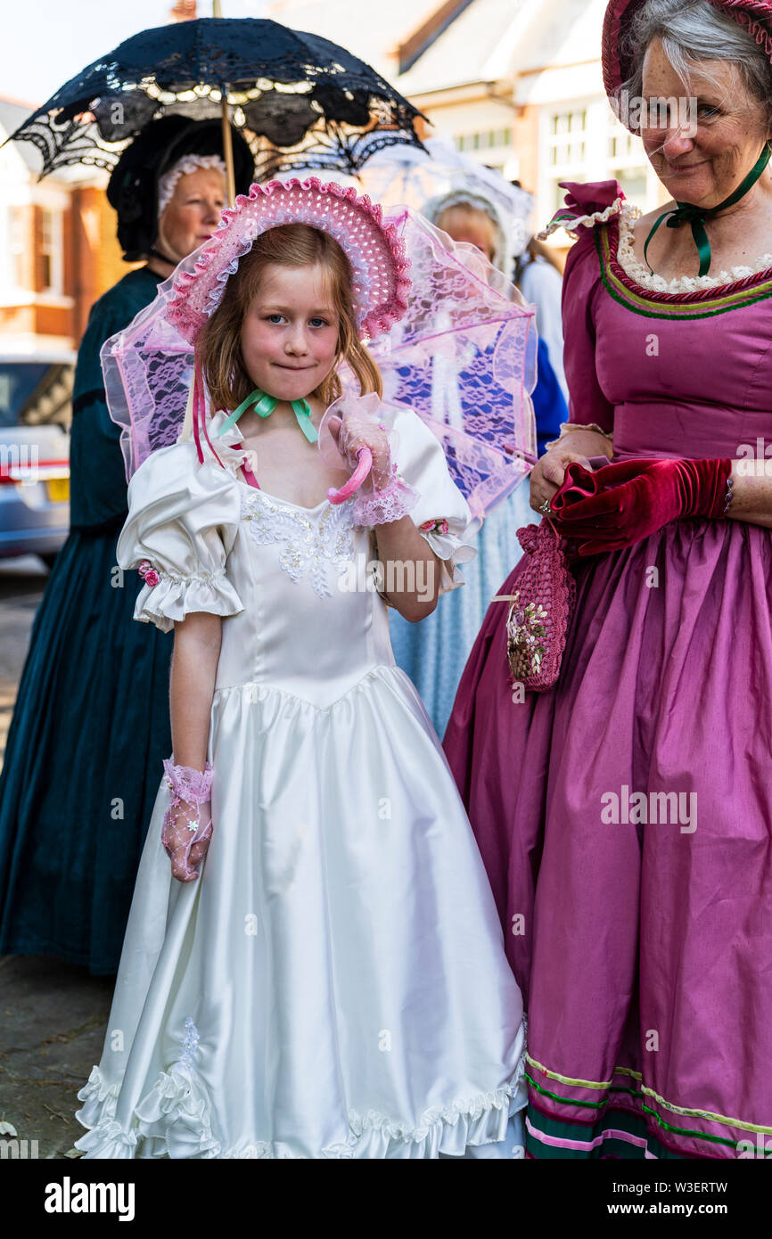 Broadstairs annuale festival Dickens. Bambino, ragazza, 8-10 anni in posa di Victorian abito bianco e rosa cofano con ombrellone rosa. Contatto visivo. Foto Stock