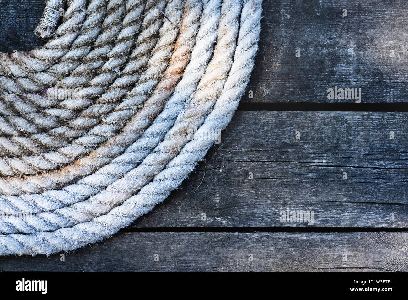 Close-up di una cima di ormeggio con una estremità annodata legato attorno un gancio su un molo in legno. Mar baltico Foto Stock