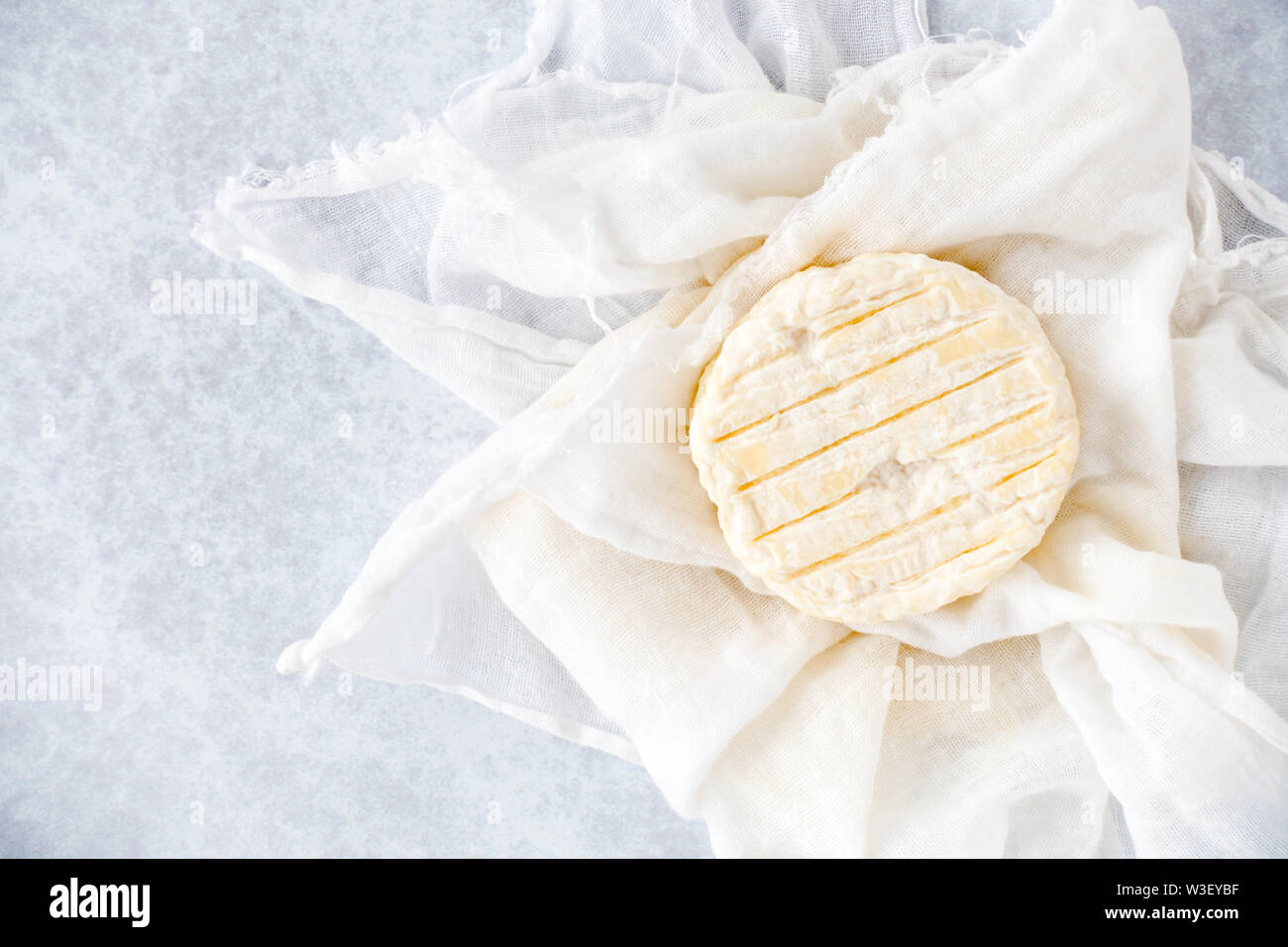 Piccolo giro soft formaggio di vacca su bianco MUSSOLA Tessuto e blu sullo sfondo a motivi geometrici. Vista dall'alto. Foto Stock