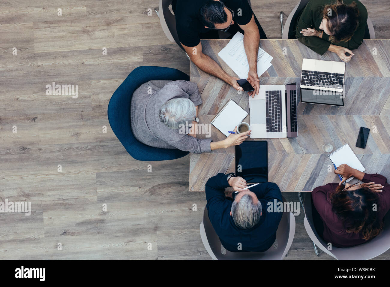 Vista superiore od senior imprenditrice discutendo con i suoi collaboratori. Riunioni di team aziendali in ufficio. Foto Stock