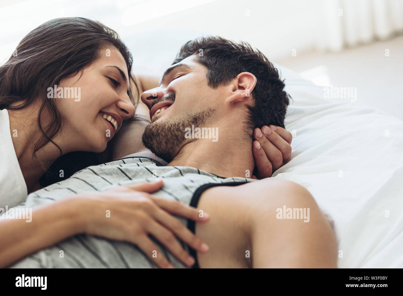 Coppia giovane disteso a letto insieme. Coppia romantica in amore guardando ogni altro e sorridente. Foto Stock