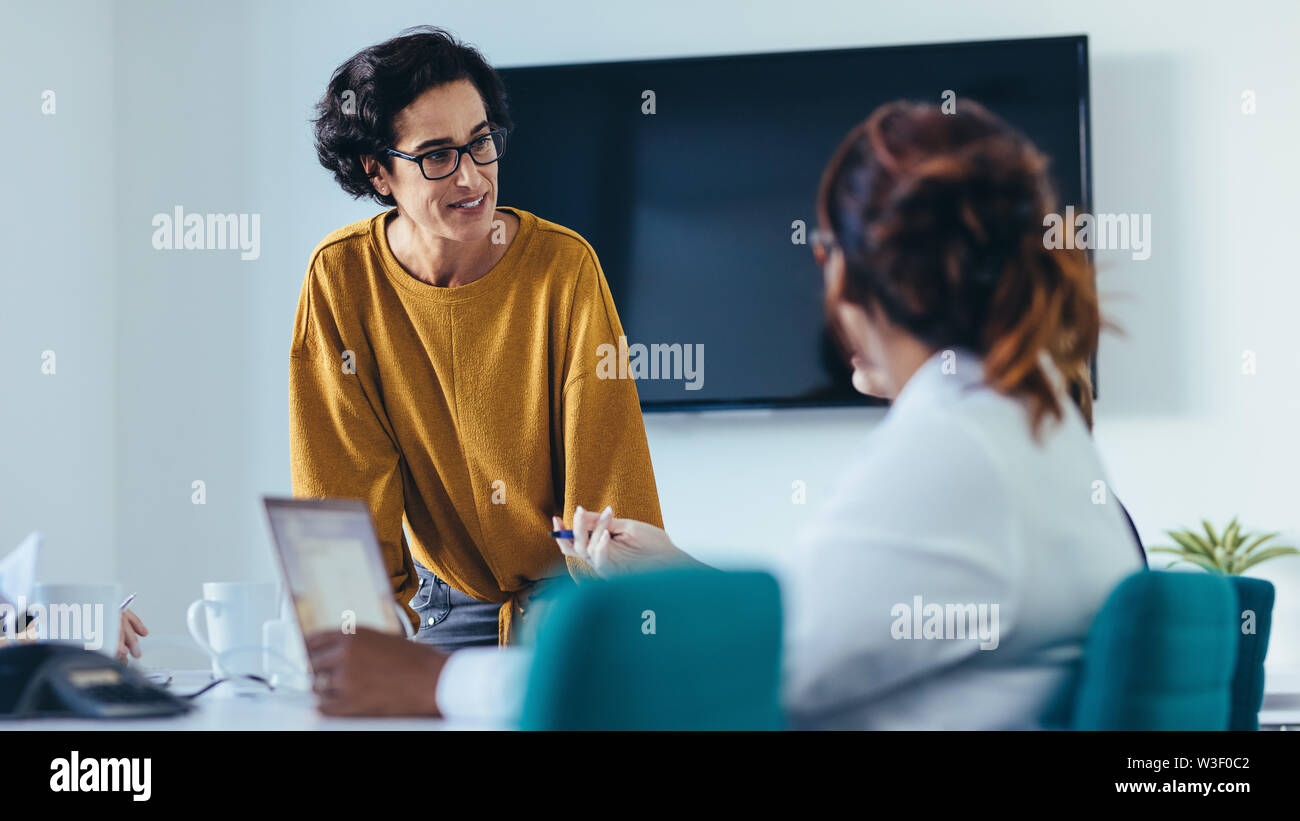 donna d'affari che parla con il suo team nella sala riunioni. gruppo di lavoro che organizza una riunione in un ufficio moderno. Foto Stock