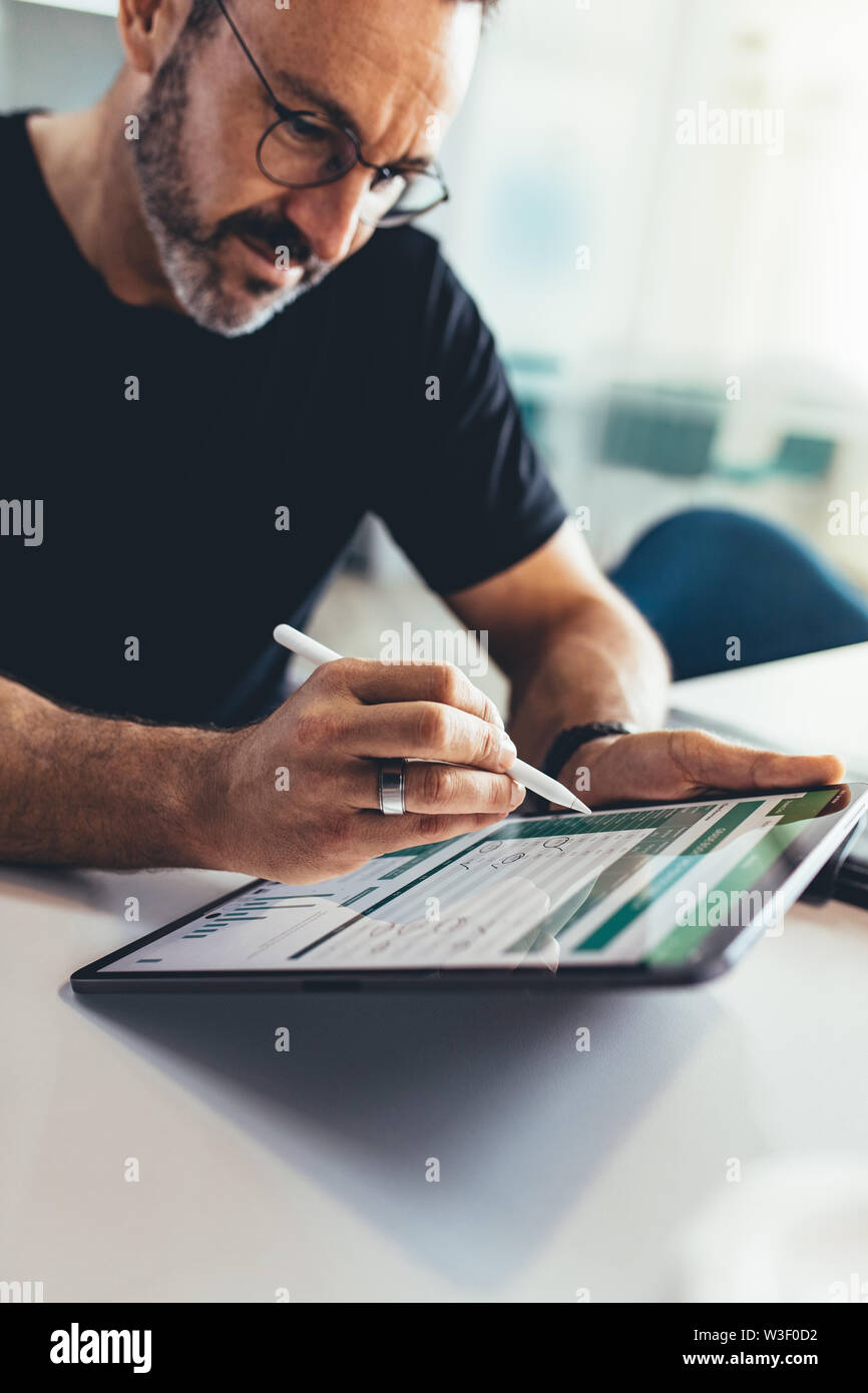 Imprenditore lavora su tavoletta digitale con uno stilo. Imprenditore maschio controllare alcuni report finanziari sul suo computer tablet. Foto Stock