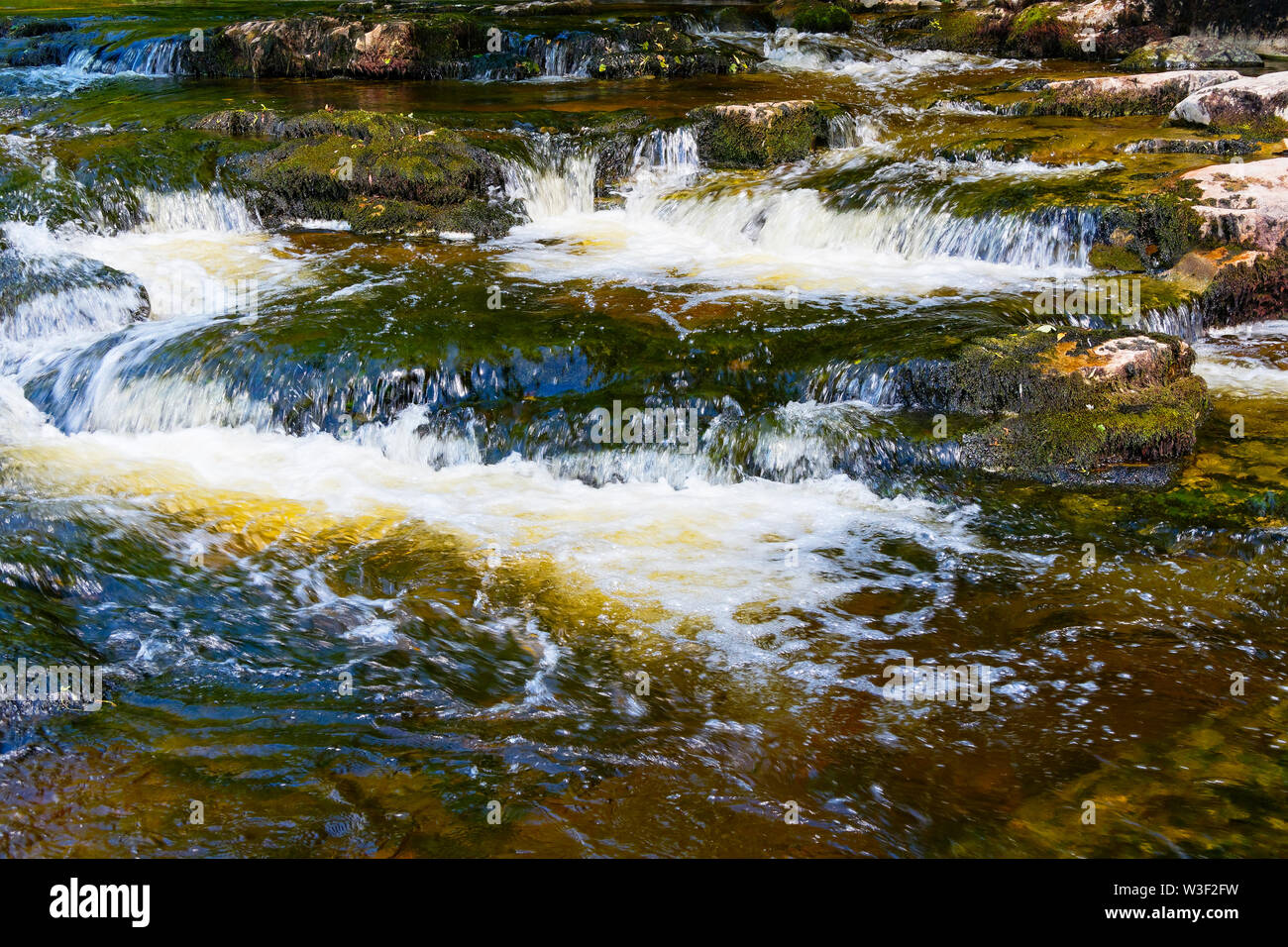 Le chiare acque del fiume Ribble diventa sfocata come si passa su rocce vicino Stainforth nel Yorkshire Dales Foto Stock