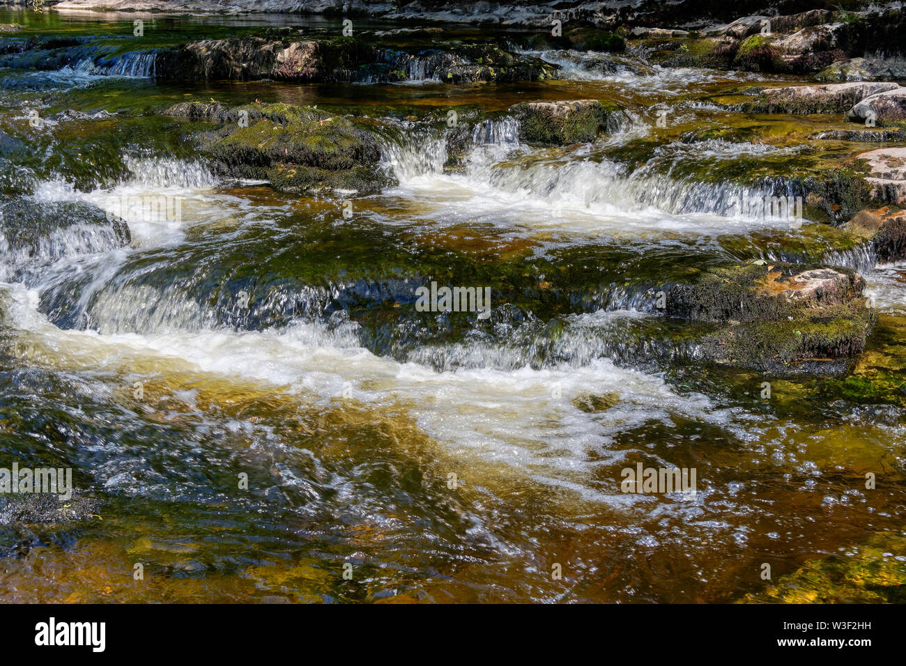 Veloce che scorre acqua del fiume Ribble inizia a blurr come cade sulle rocce a forza di Stainforth Foto Stock