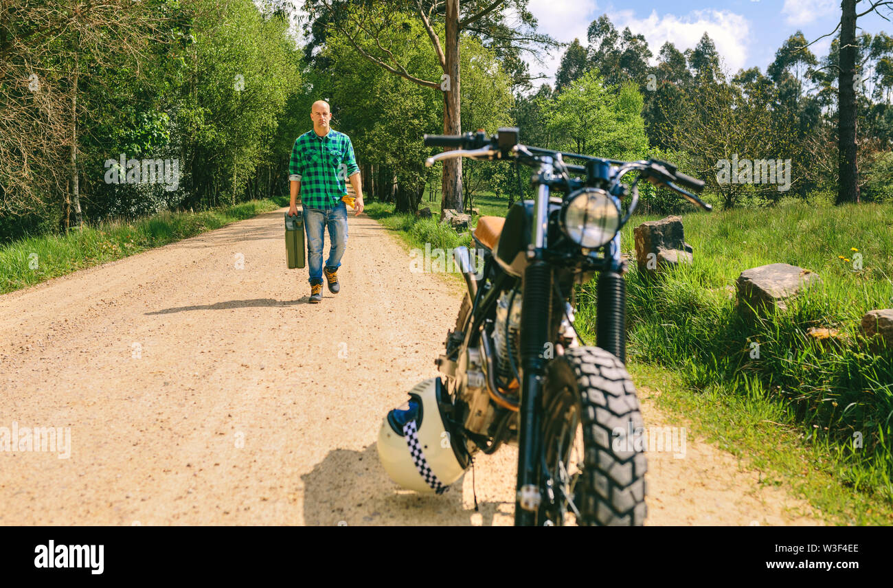 Uomo con benzina può raggiungere a piedi personalizzato moto d'epoca Foto Stock