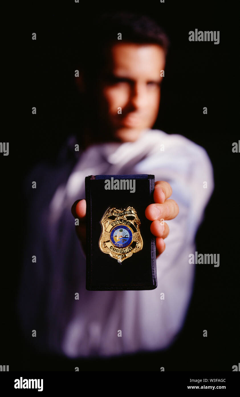 Detective tenendo il suo badge per la fotocamera Foto Stock