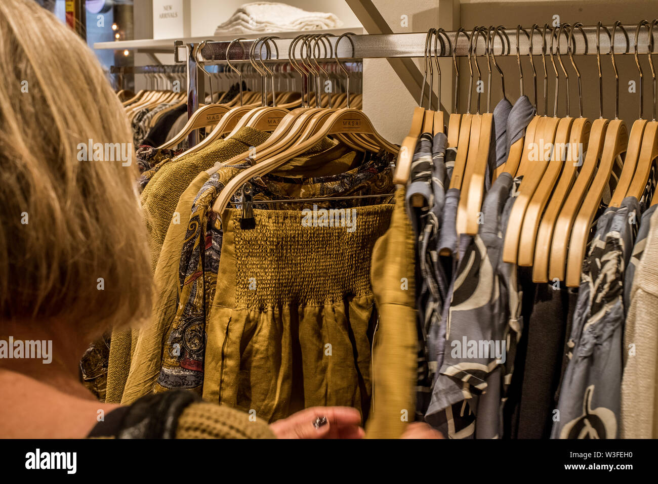 Donna abiti da shopping da appendiabiti in una boutique scandinavo in Malmoe, Svezia, 22 maggio 2019 Foto Stock