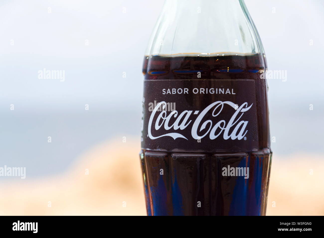 EL Medano, Spagna - 10 luglio 2019: Coca Cola Company logo sulla bottiglia di vetro con coke con mare in background sulla luglio 10, 2019 a El Medano, Spagna. Foto Stock