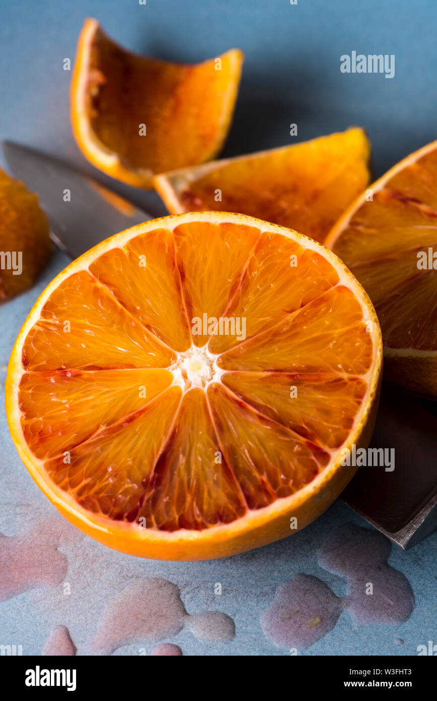 Dimezzato il sangue arancione con buccia e coltello, visualizzazione verticale Foto Stock