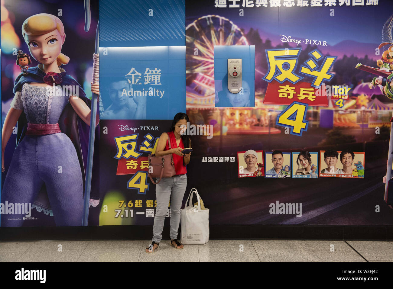Hong Kong, Cina. 14 Luglio, 2019. Un " commuter " sorge accanto ad un grande Pixar Animation Studios Toy Story 4 film wall pubblicità in Hong Kong MTR stazione della metropolitana. Credito: Budrul Chukrut SOPA/images/ZUMA filo/Alamy Live News Foto Stock