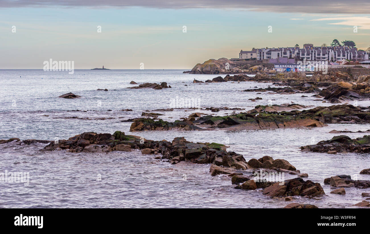 Costa rocciosa vicino a 40 piedi a Sandycove, Irlanda con Muglins faro a distanza Foto Stock